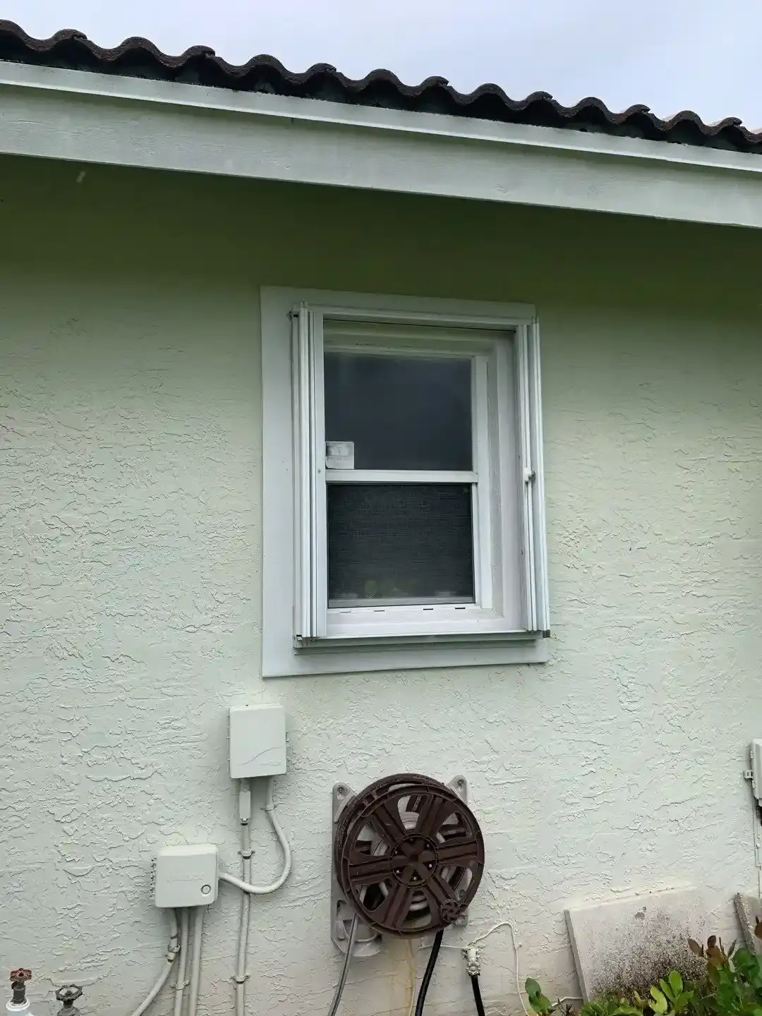 Accordion shutter housing mounted beside a window opening