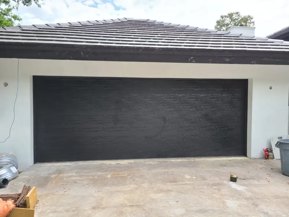 Dark grey garage door installed on a South Florida driveway elevation