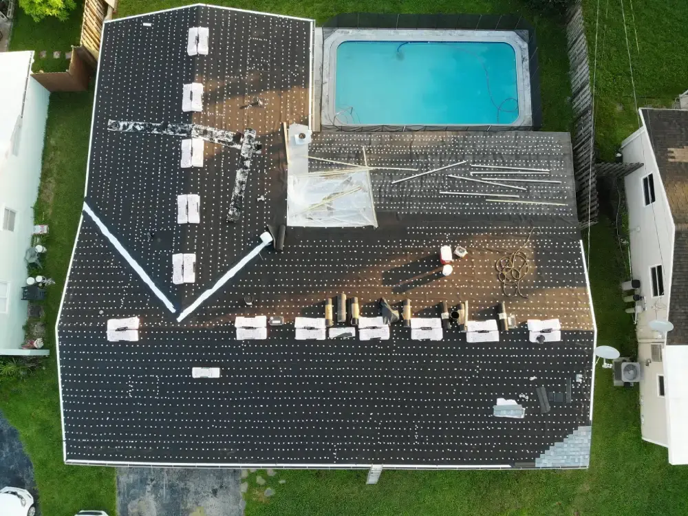 Overhead drone view of a South Florida house dried in with underlayment and tin-cap fasteners after a full tear-off